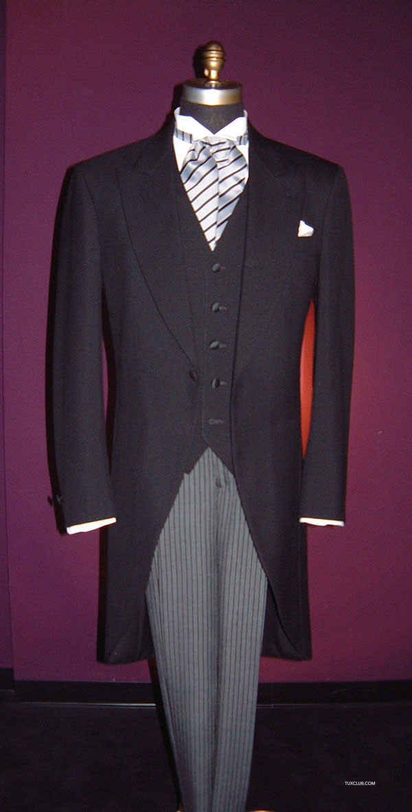 Black long cutaway morning suit with white shirt and cravat on a mannequin against a purple background
