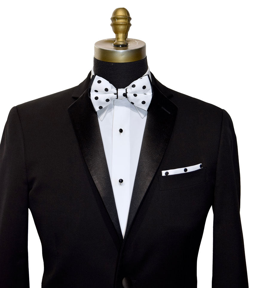Black tuxedo with a white shirt and black and white polka dot bow tie on a mannequin.