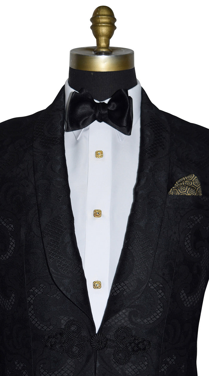 close-up front view Black tuxedo with white shirt and bow tie on a mannequin wearing gold baroque cufflinks and studs against a white background