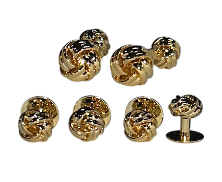 Set of gold love knot-shaped cufflinks and studs on a white background