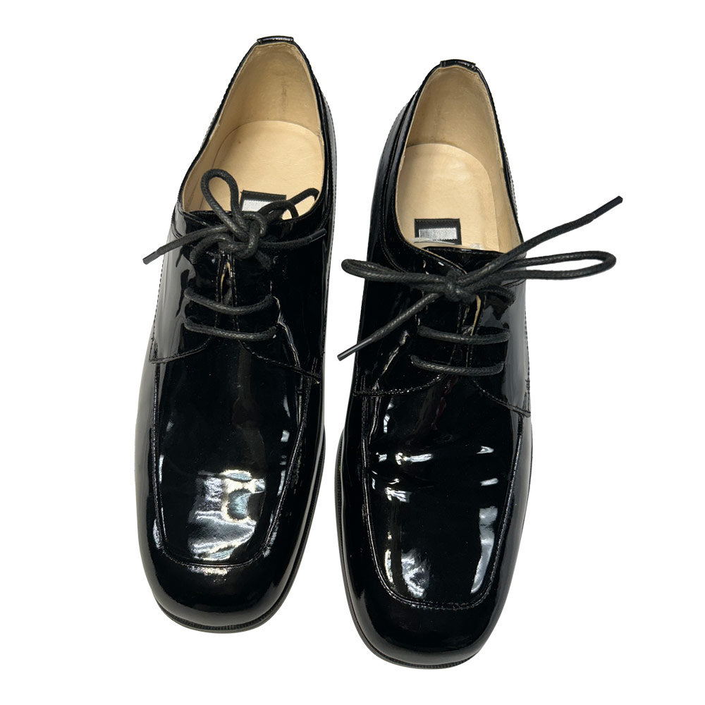 Pair of black patent leather shoes with laces on a white background