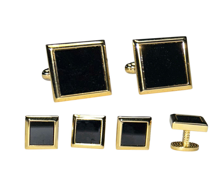 Set of black square cufflinks and studs with gold setting on a white background