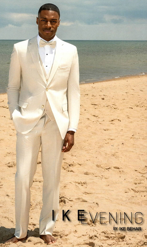 Black Model wearing tan-fitted wedding suit with tan vest and tan bowtie standing on the beach.