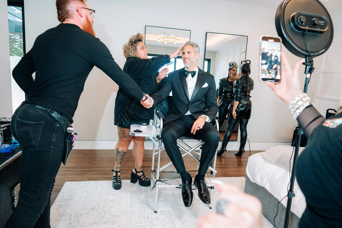 handsome man wearing a black peak lapel tuxedo while getting hair styled before the San Diego Film Festival.
