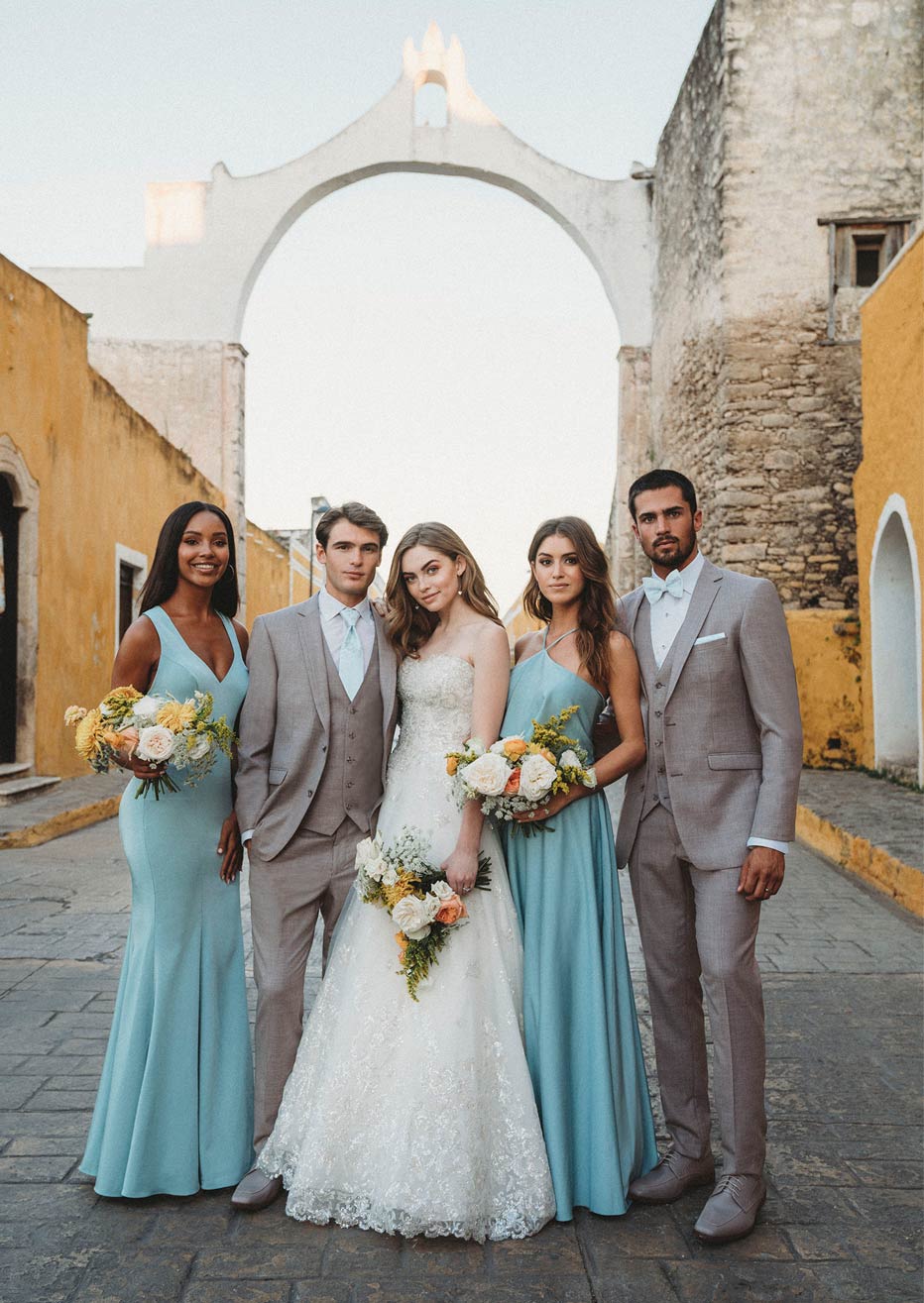 Wedding group wearing gray suits while standing in front of a historical building in Mexico.