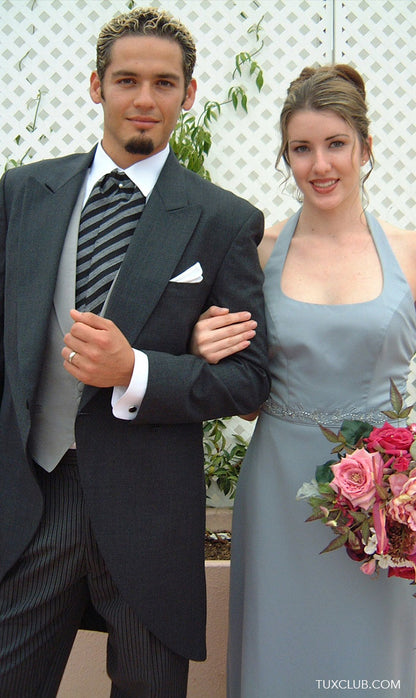 man wearing a charcoal cutaway morning suit standing next to bridesmaid at a wedding reception