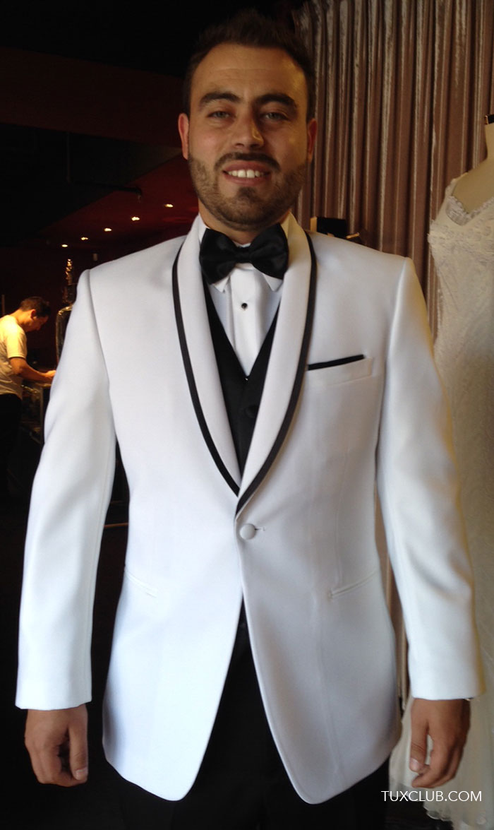 Man wearing a white tuxedo with black trim and black satin bowtie in a tuxclub tuxedo shop