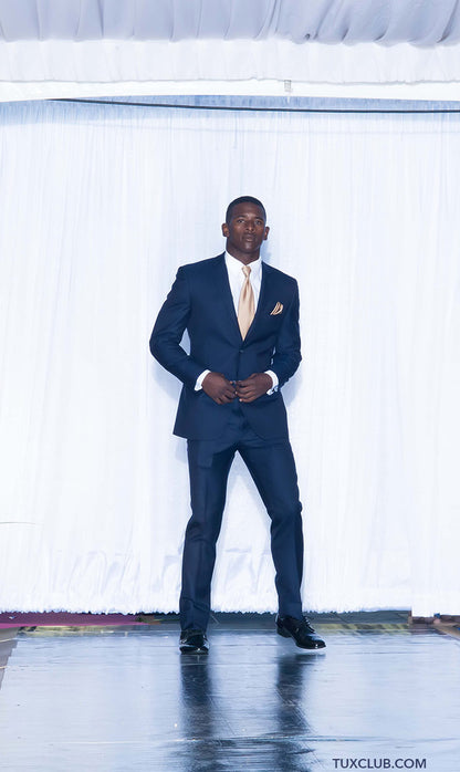Handsome black man wearing a navy slim-fit suit with a white shirt and gold tie on a stage