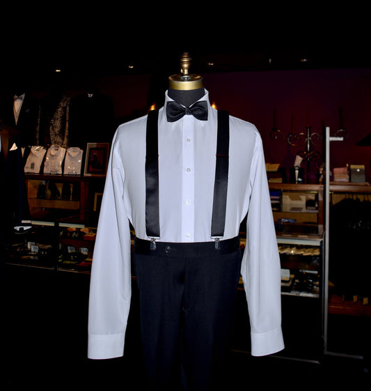 White dress shirt with black satin suspenders and black bow tie on a mannequin inside a tuxedo shop