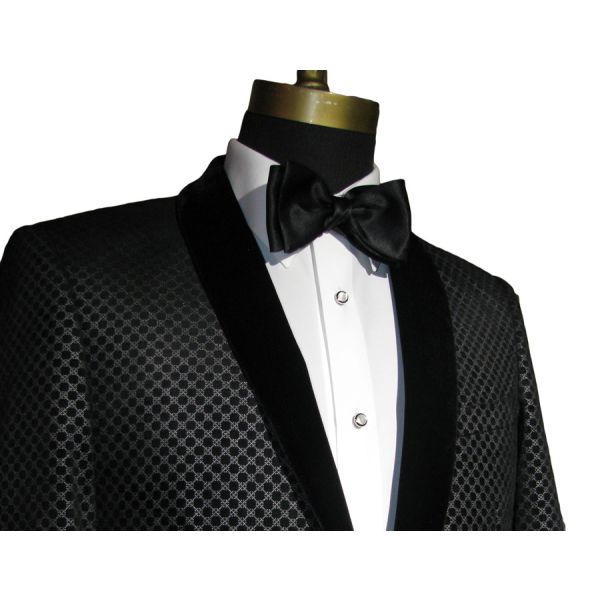 close-up black velvet tuxedo with geometric design shown with pearl studs and cufflinks and a black bowtie against a white background