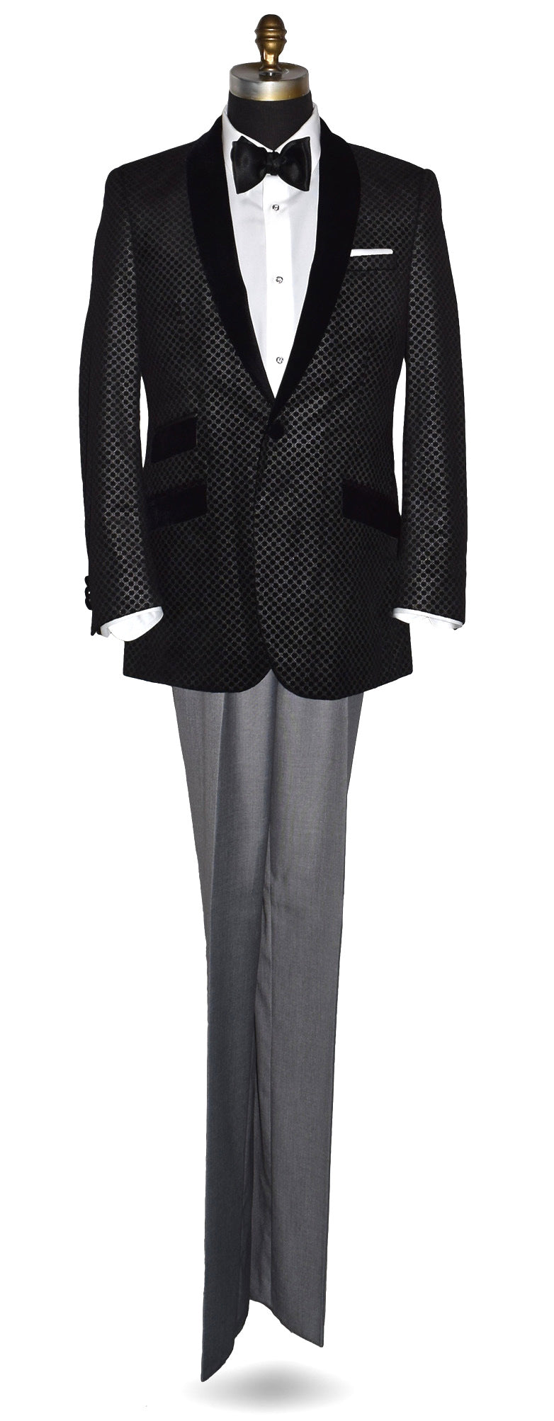 life size mannequin wearing a black velvet tuxedo with silver geometric design against a white background