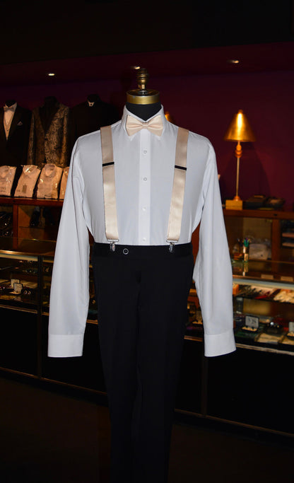 Mannequin wearing a white dress shirt with champagne satin suspenders and black pants in a tuxedo shop setting.