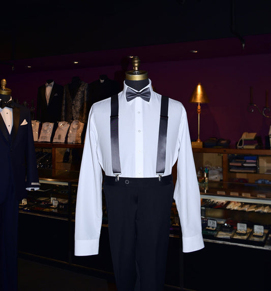 Mannequin wearing a white dress shirt with charcoal satin suspenders and charcoal bow tie inside a tuxedo shop