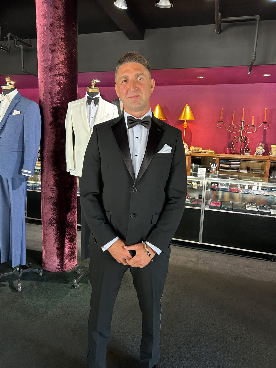 close-up man wearing a black notch lapel tuxedo in a tuxedo shop