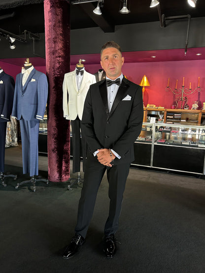 Man wearing a black dkny tuxedo in a tuxedo shop