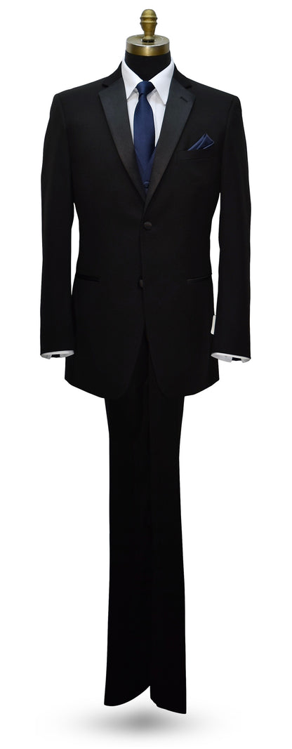 life-size mannequin wearing a black notch-lapel tuxedo with a marine-blue striped necktie and marine-blue tuxedo vest against a white background