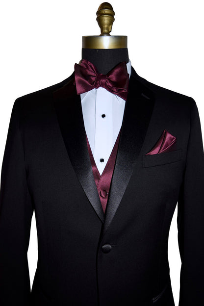 front view Black tuxedo with a wine "tie-yourself" bow tie and wine colored vest and pocket square on a mannequin against a white background.