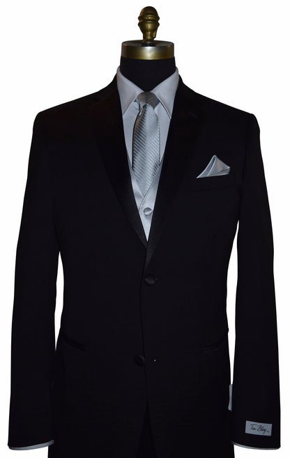 Black wedding suit with a "Tux Bling" branded label on the sleeve on a mannequin with a white shirt, silver necktie and silver vest, and pocket square.