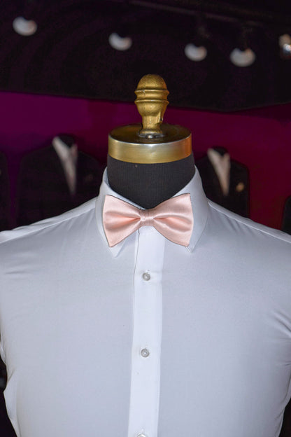 Mannequin wearing a white dress shirt with a blush pre-tied bow tie against a dark background