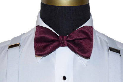 wine bow tie on a white dress shirt with white suspenders