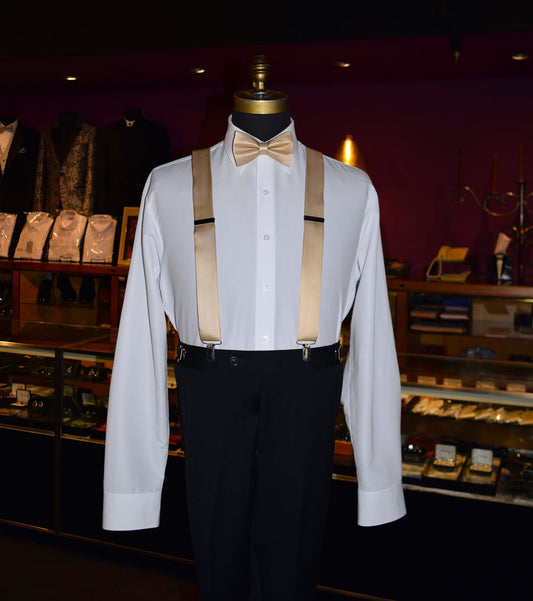 Mannequin wearing a white dress shirt with gold satin suspenders and a gold bow tie in a tuxclub men's store.