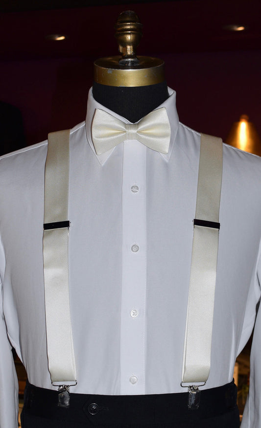 Mannequin wearing a white dress shirt with ivory satin suspenders and a ivory satin bow tie against a dark background