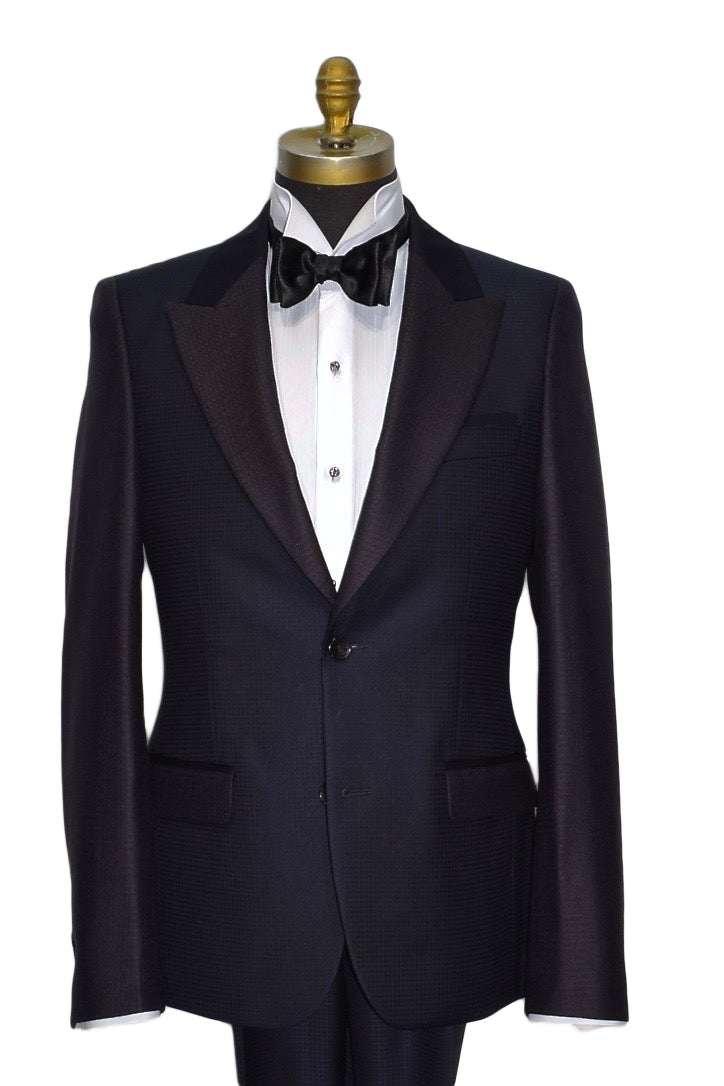 navy blue peak lapel tuxedo on a mannequin with a white tuxedo shirt and a black satin bowtie with studs and cufflinks on the tuxedo shirt
