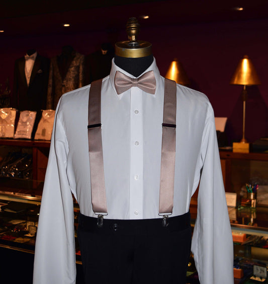 Mannequin wearing a white dress shirt with rose-gold satin suspenders and bow tie inside  tuxedo shop