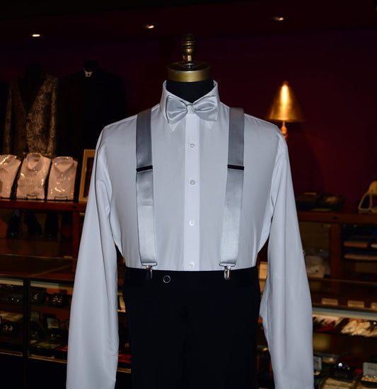 Mannequin wearing white dress shirt with silver satin suspenders and silver bowtie with black pants at tuxcedo store.