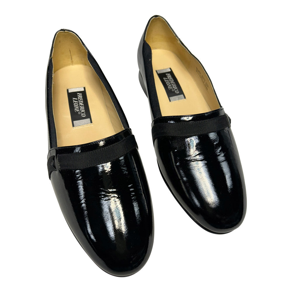 Pair of black patent leather loafers on a white background