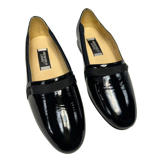 Pair of black patent leather loafers on a white background