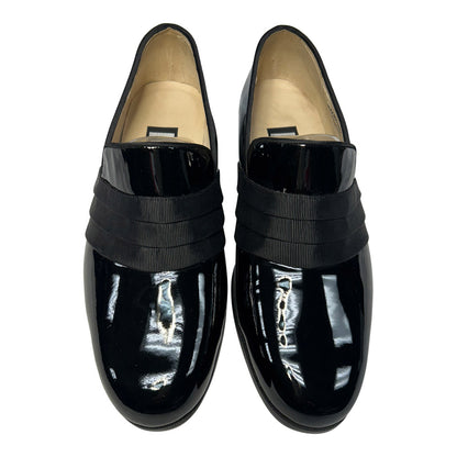 close-up view Pair of black patent leather slip-on shoes with a grosgrain ribbon detail on a white background