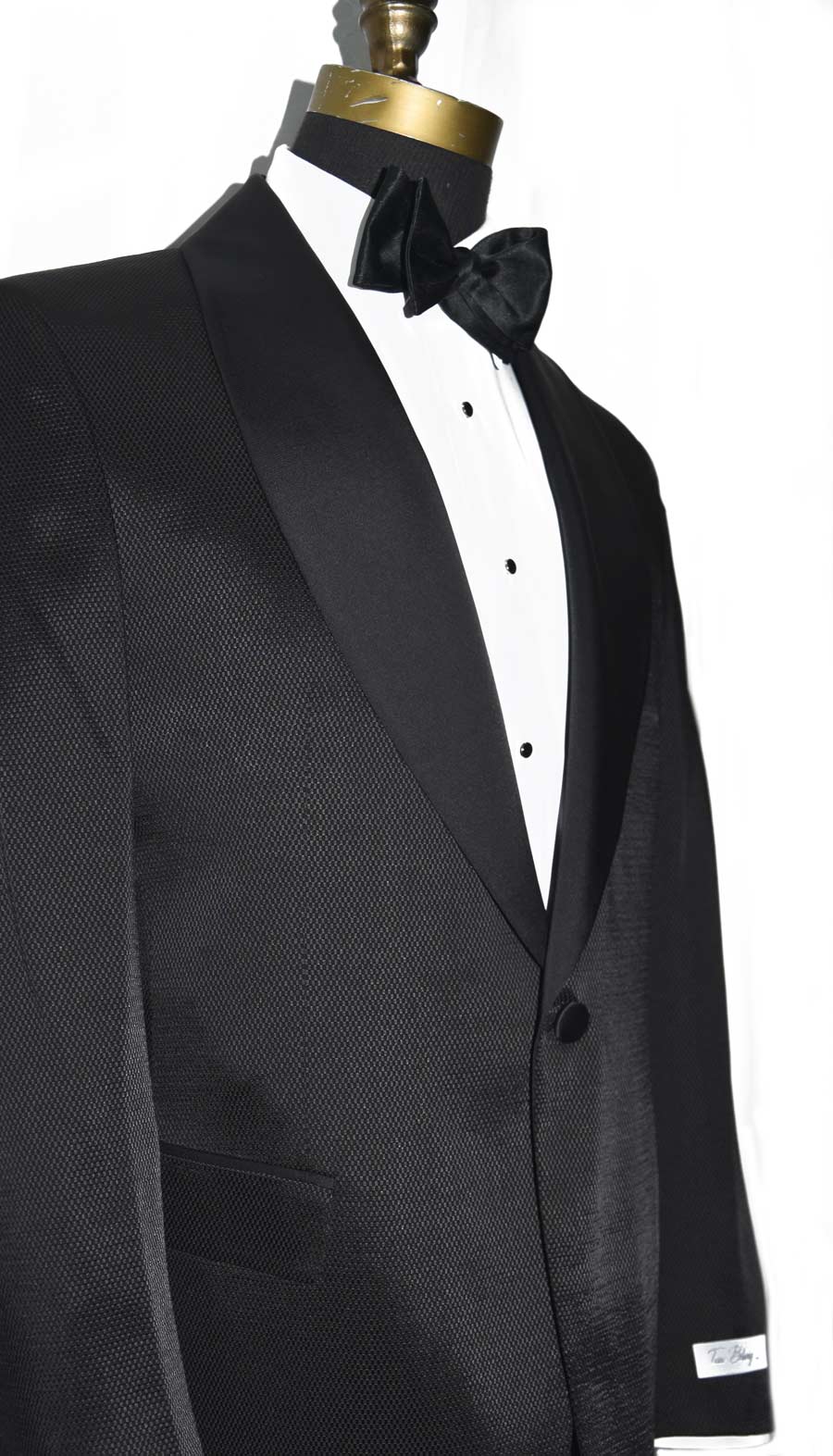 size view black shawl collar tuxedo with slight texture with black satin bowtie gainst a white background with a "tux Bling" brsnded label