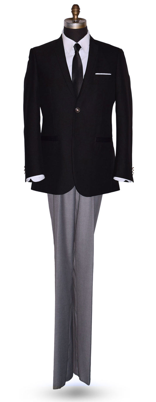 life size mannequin wearing a black sports coat with a white dress shirt and black satin necktie with gray pants in-front of a white background