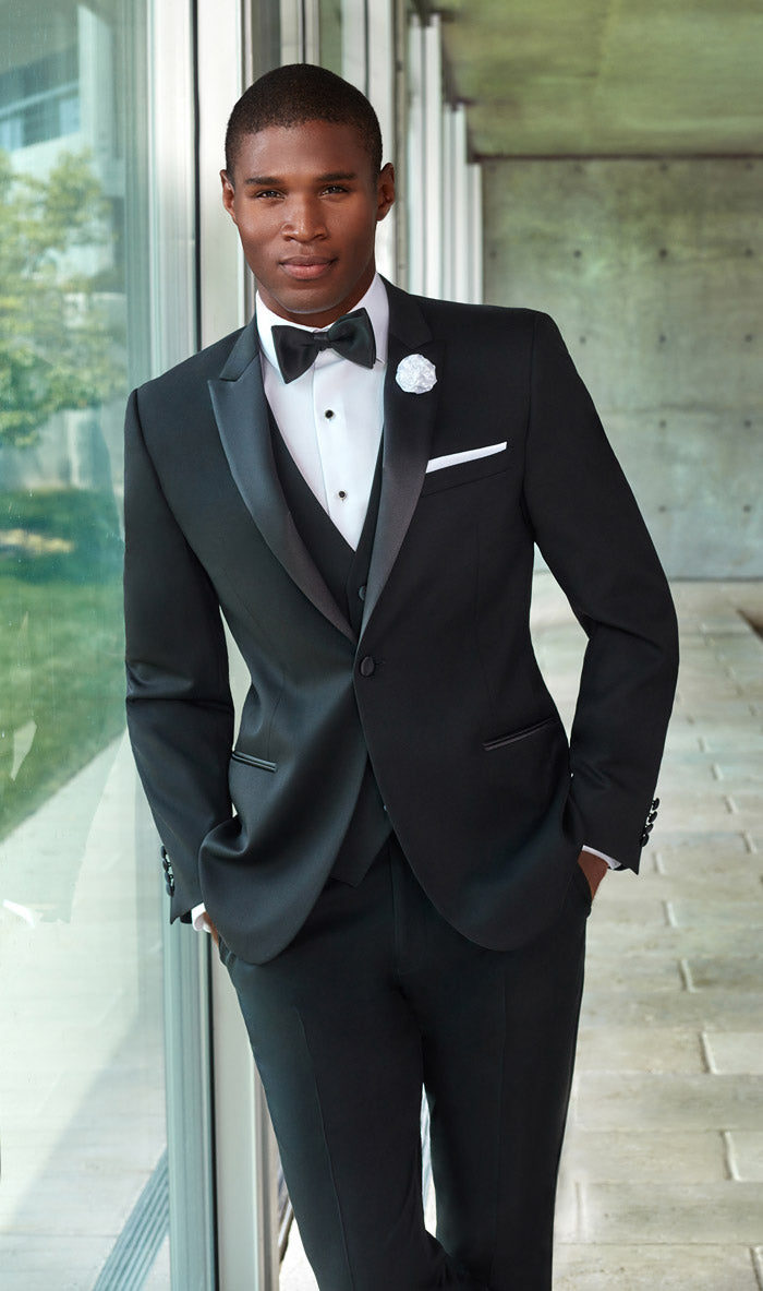 Best man wearing black peak lapel tuxedo in modern building