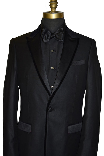 close-up life size mannequin wearing a black peak lapel tuxedo with velvet trim on the lapel with a black tuxedo shirt and black satin tie-yourself bowtie against a white background
