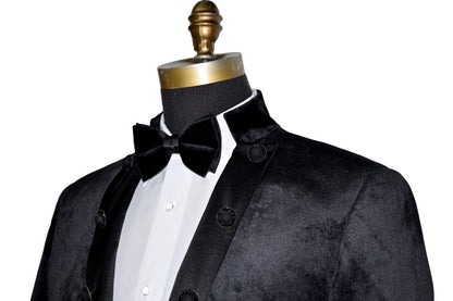 side view black velvet nehru collar tuxedo jacket with a black bowtie against a white background
