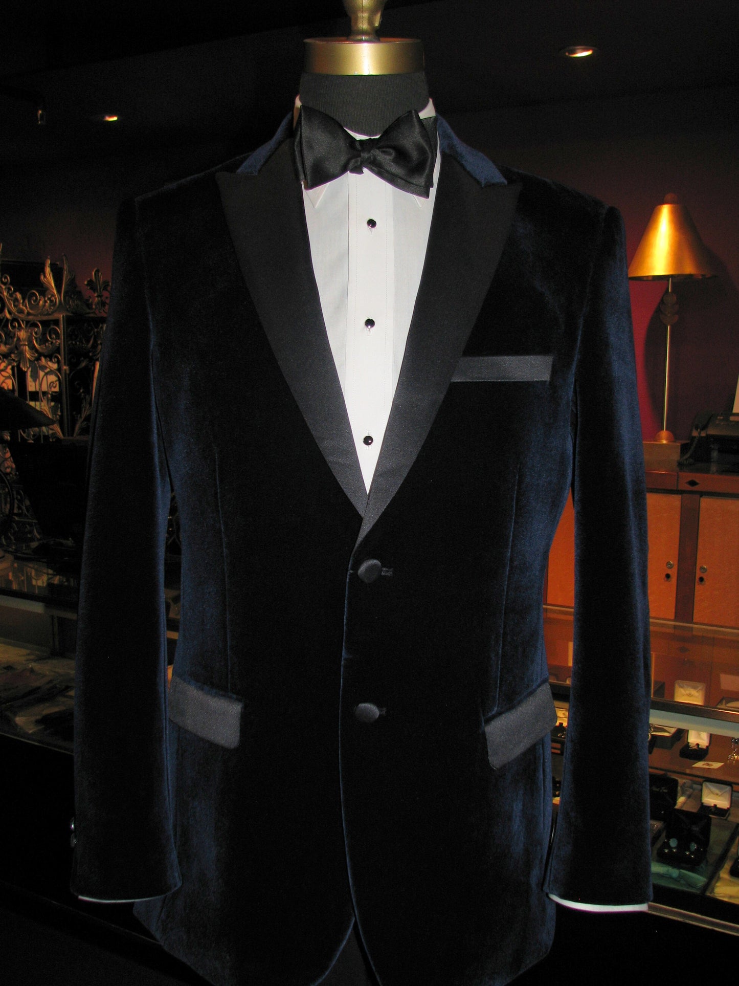 mannequin wearing a black velvet tuxedo with a black bowtie in a fancy tuxedo shop