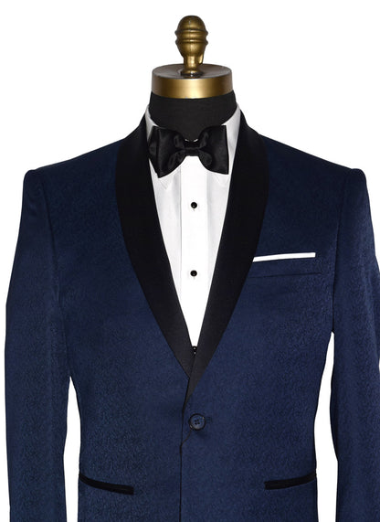 close-up front view-Navy blue tuxedo with black shawl collar with a brocade print on a mannequin with black tuxedo pants and a white tuxedo shirt and black satin bowtie in front of a white background