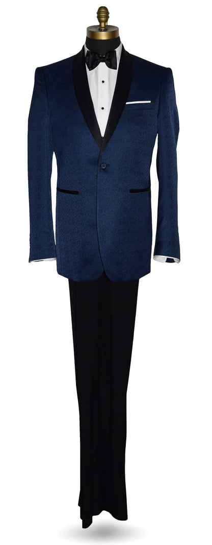 Navy blue tuxedo with black shawl collar with a brocade print on a mannequin with black tuxedo pants and a white tuxedo shirt and black satin bowtie in front of a white background