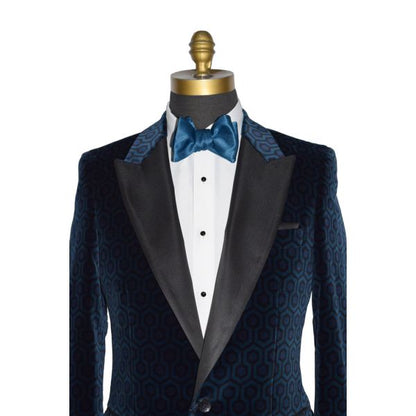 very close up mannequin wearing a blue velvet tuxedo jacket with a white tuxedo shirt and blue tie-yourself bowtie against a white background