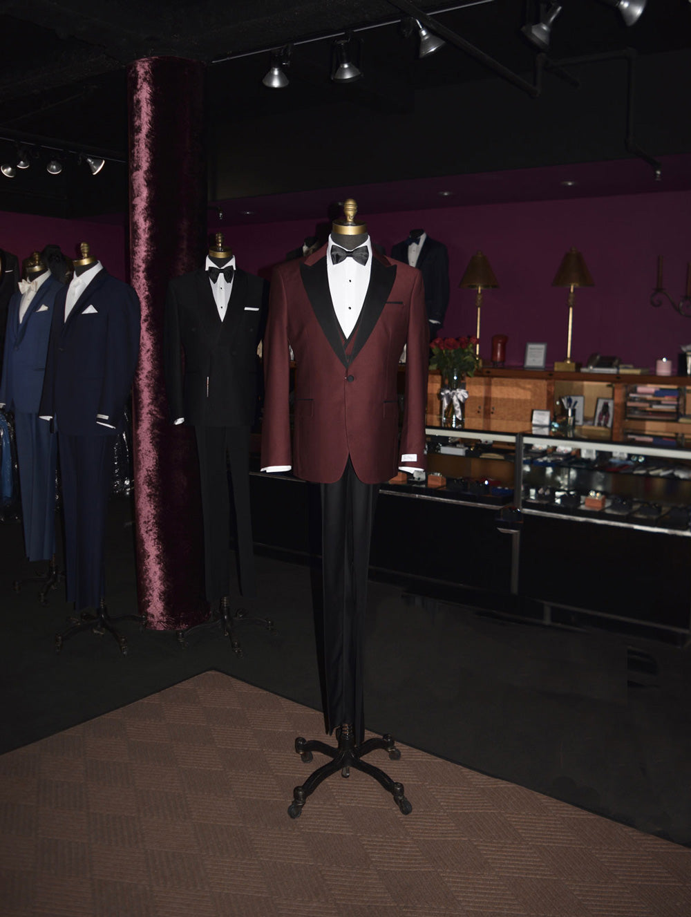 life-size mannequin wearing burgundy 3 piece tuxedo with black lapels and a black bowtie inside a fine tuxedo shop