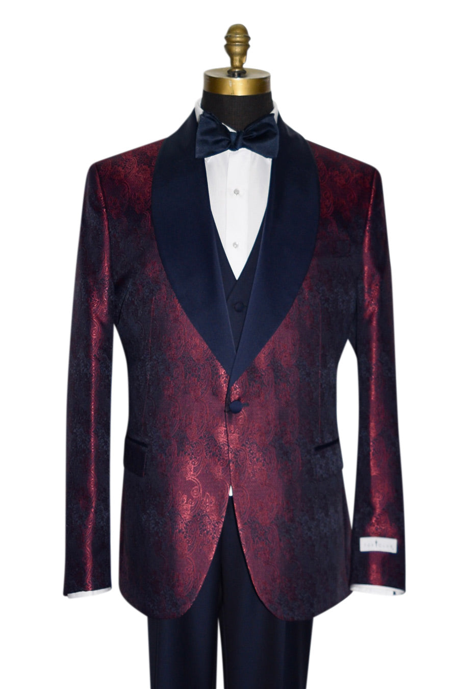 close-up  mannequin wearing a burgundy dinner jacket with navy blue lapel and navy blue paisley design with black pants against a white background