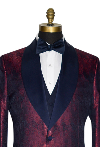 super close mannequin wearing a burgundy dinner jacket with navy blue lapel and navy blue paisley design with white tuxedo shirt against a white background