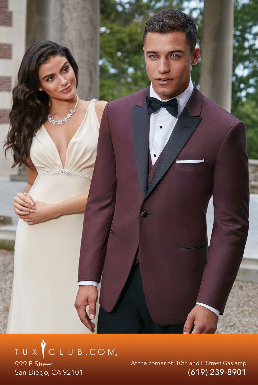 Man in a burgundy tuxedo and woman in a white dress standing outdoors, with Tux Club.com branding at the bottom.