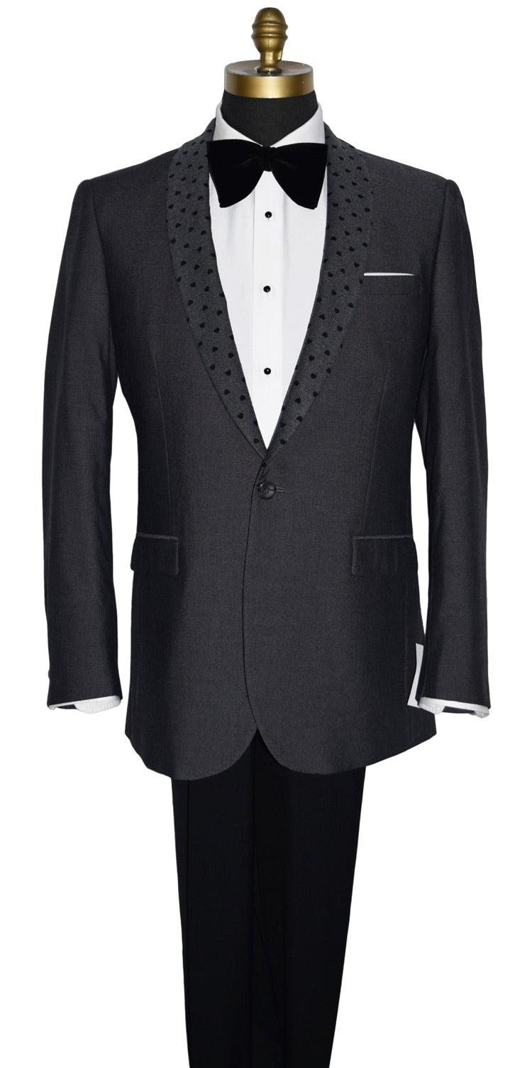 close-up life size mannequin wearing a charcoal gray dinner jacket with a white shirt and larger black velvet bow tie on a mannequin against a white background