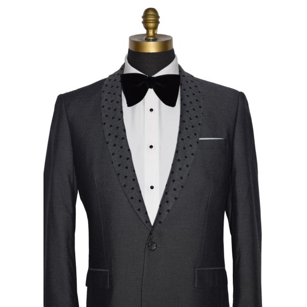close-up detailed view mannequin wearing a charcoal gray dinner jacket with a white shirt and larger black velvet bow tie on a mannequin against a white background