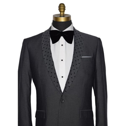 close-up detailed view mannequin wearing a charcoal gray dinner jacket with a white shirt and larger black velvet bow tie on a mannequin against a white background