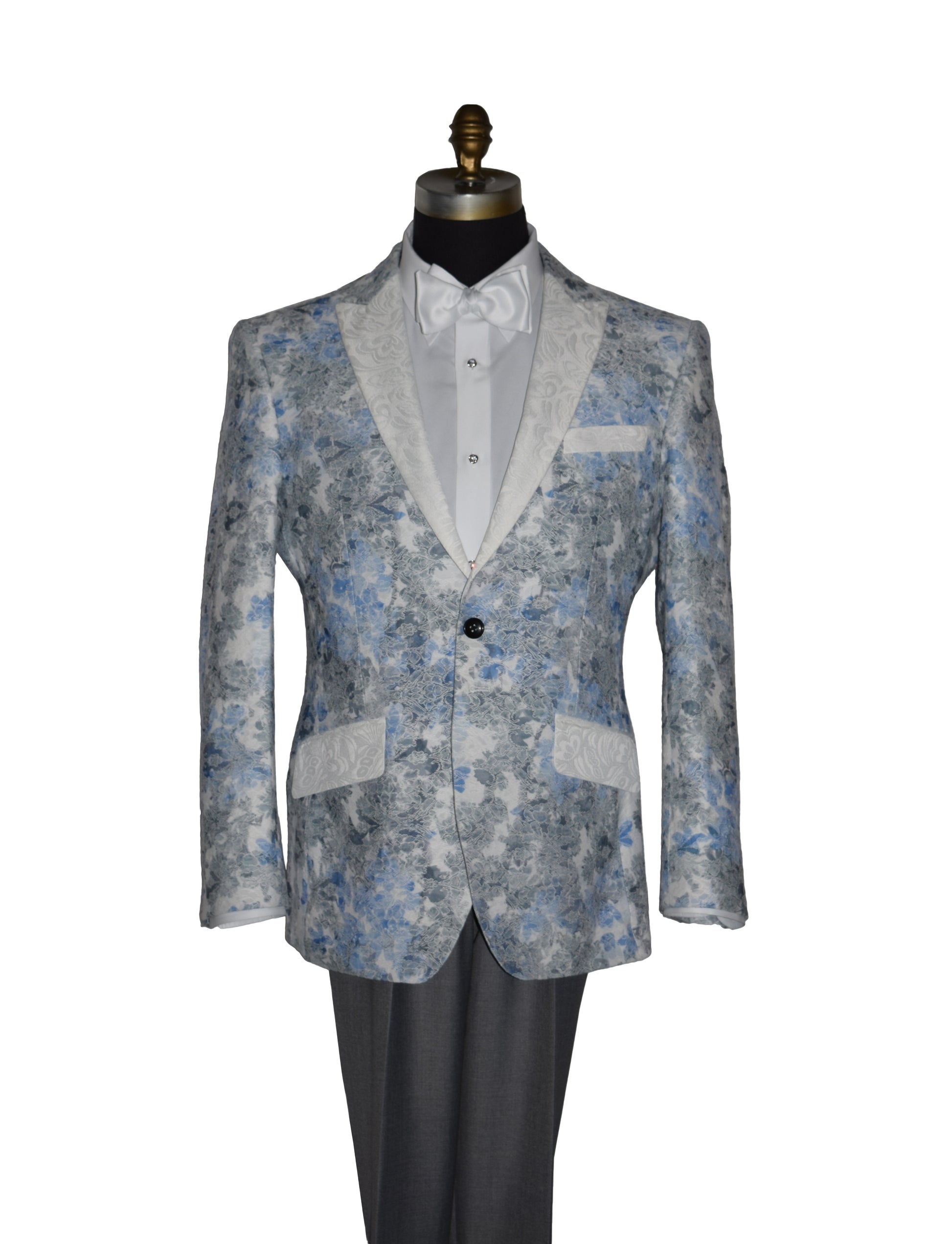 close-up blue and gray floral-patterned tuxedo jacket with a white bowtie and gray pants on a mannequin against a white background