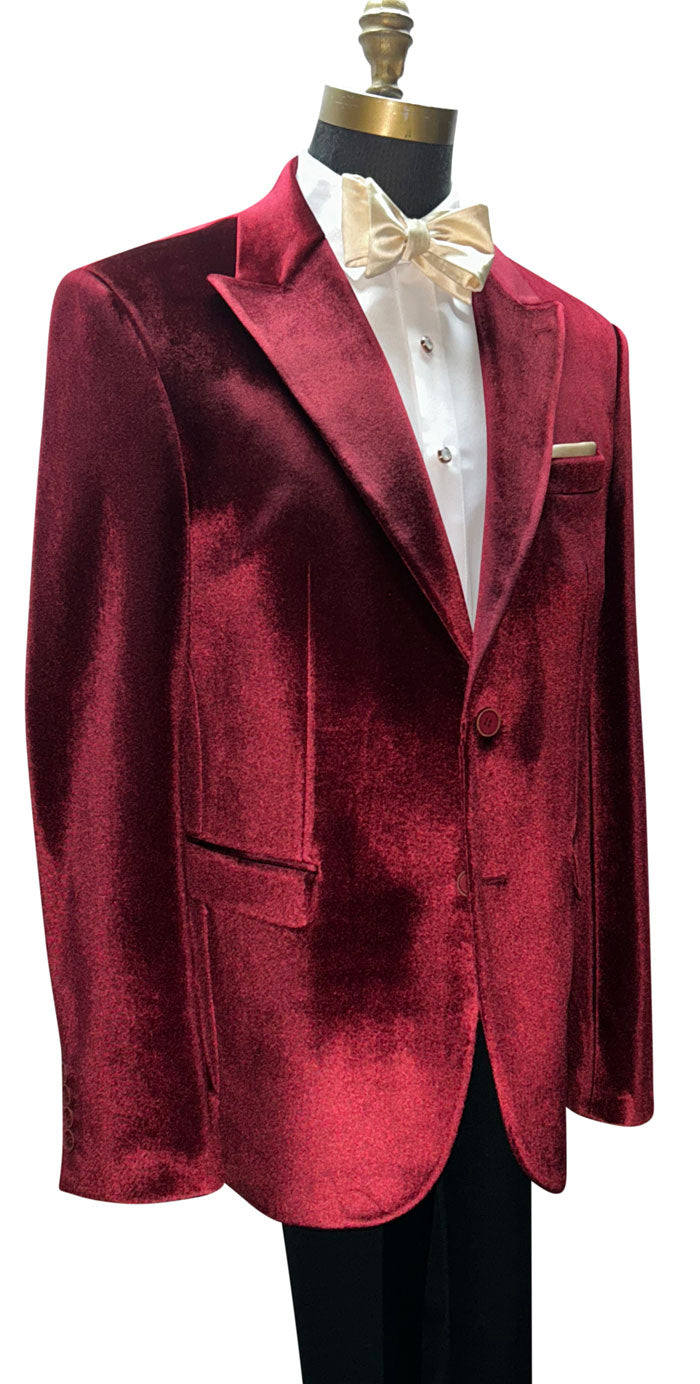 close up left size burgundy crimson red velvet dinner jacket with a white shirt and a champagne bowtie against a white background